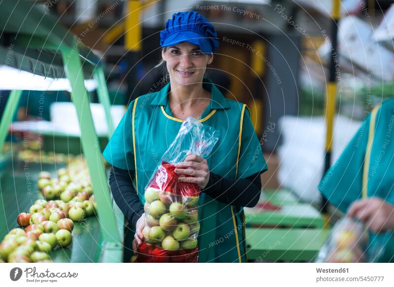 Portrait of smiling woman holding apples in plastic bags in factory females women working At Work Apple Apples smile Plastic Bags plastig bags portrait