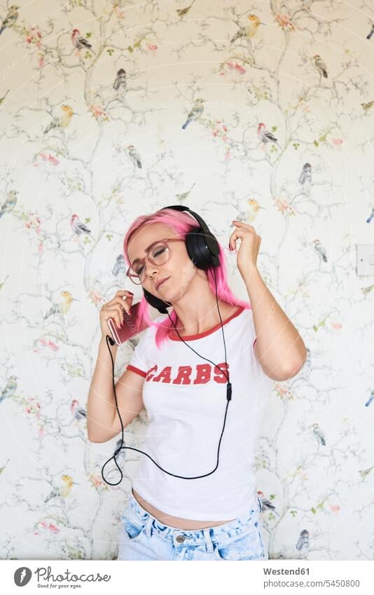 Enthusiastic young woman with pink hair listening to music at home headphones headset mobile phone mobiles mobile phones Cellphone cell phone cell phones