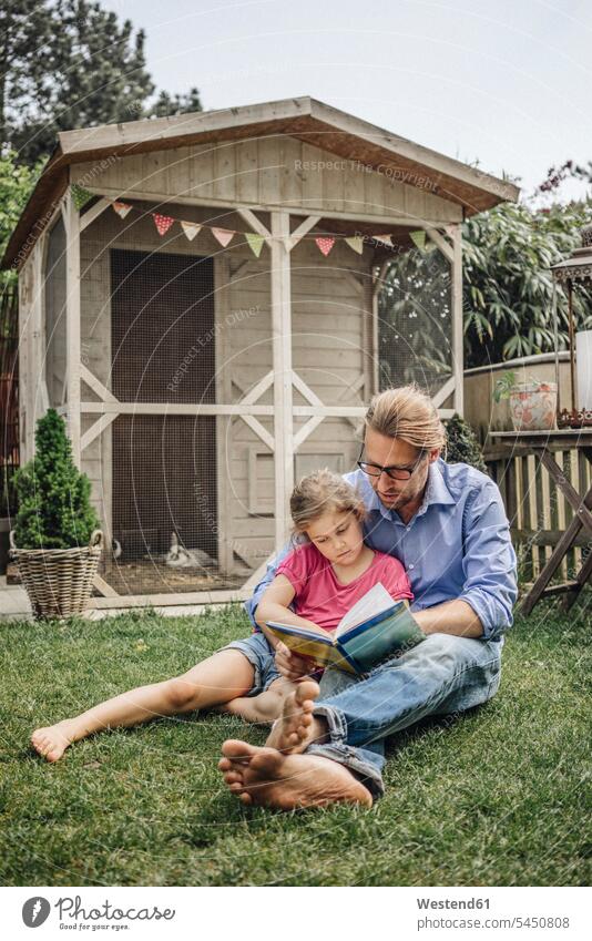Father reading book with daughter in garden books relaxed relaxation daughters gardens domestic garden father pa fathers daddy dads papa relaxing child children