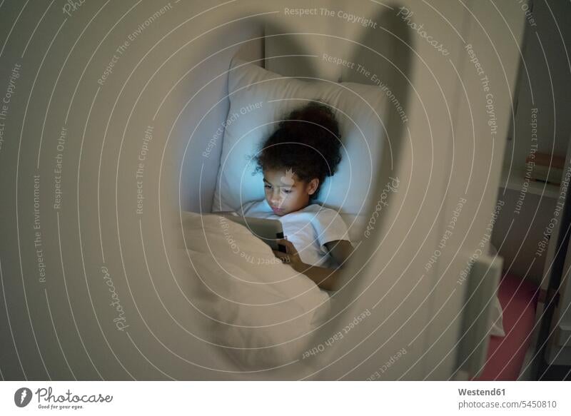 Little girl sitting in dark children's room, looking at digital tablet Kids Room nursery child's room playing reading Seated rooms domestic room domestic rooms