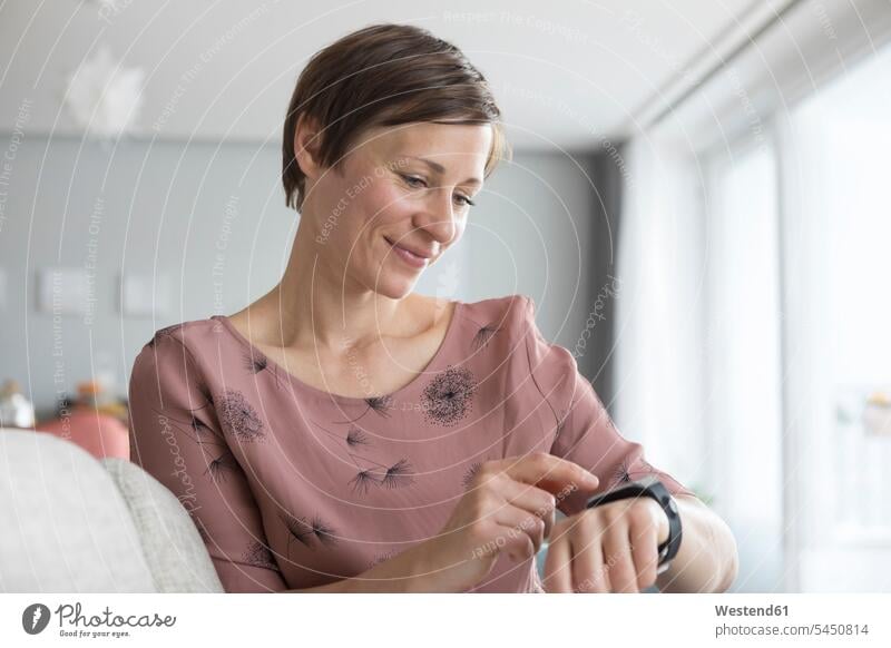 Portrait of smiling woman using smartwatch at home females women smart watch portrait portraits Adults grown-ups grownups adult people persons human being