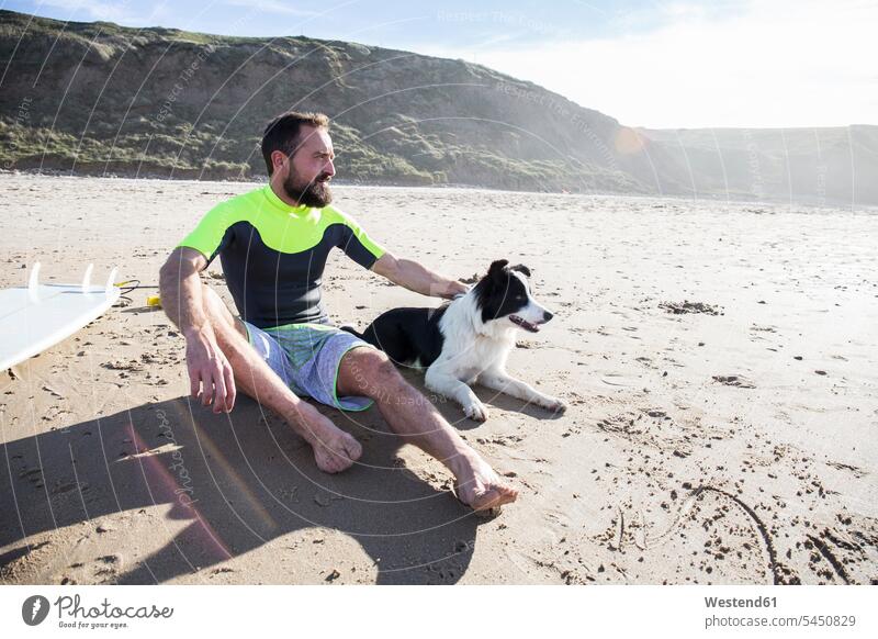 Man with dog and surfboard on the beach dogs Canine man men males beaches sitting Seated surfer surfers pets animal creatures animals Adults grown-ups grownups