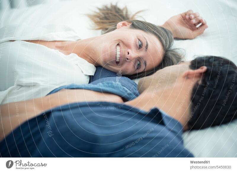 Smiling young couple in love lying down relaxed relaxation laying down lie twosomes partnership couples smiling smile relaxing people persons human being humans