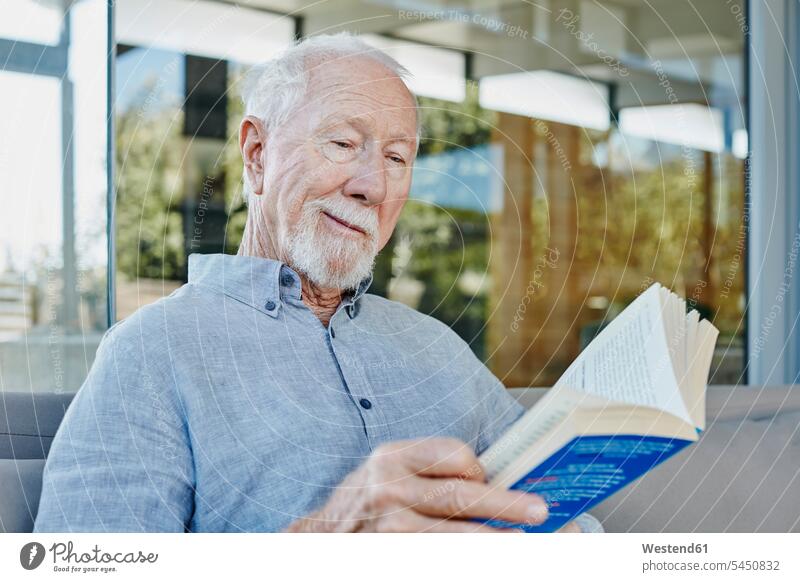 Senior man sitting on terrace reading book terraces books Seated pensioner pensioners retirees senior men senior man elder man elder men senior citizen