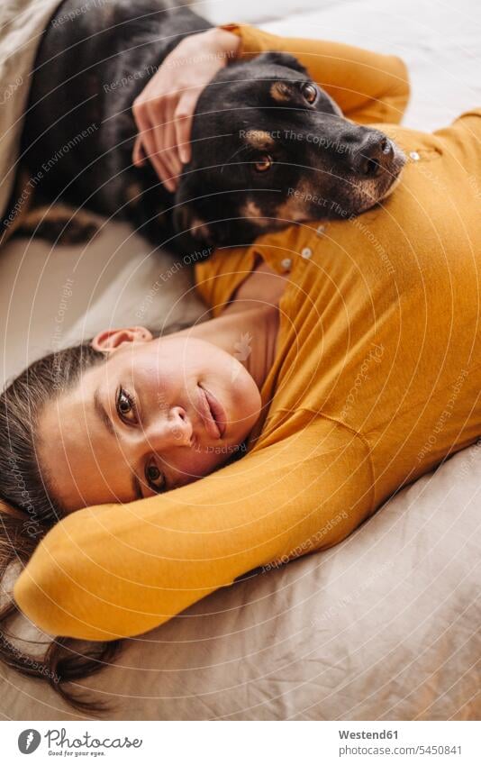 Woman lying in bed with her dog woman females women animal-loving fond of animals love of animals dogs Canine laying down lie lying down beds cuddling snuggle