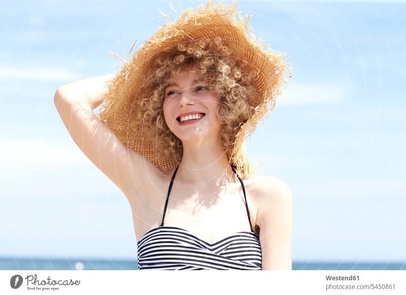 Portrait of happy young woman wearing straw hat on the beach females women hats portrait portraits Adults grown-ups grownups adult people persons human being