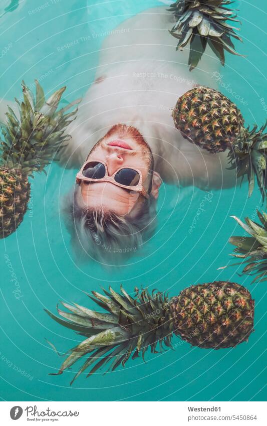 Young man in swiming pool surrounded by pineapples swimming pool pools swimming pools Pineapple Ananas comosus Ananas sativus Pineapples men males Fruit Fruits