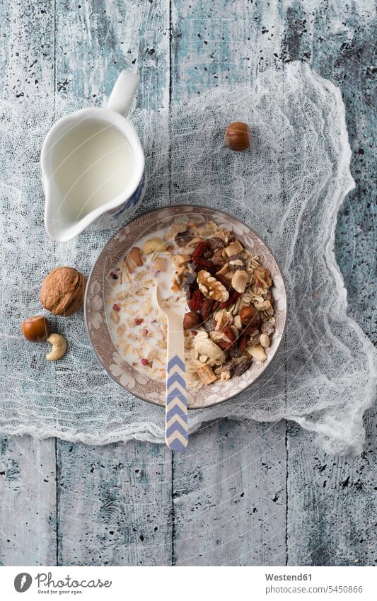Bowl of granola with nuts and a jug of milk Bowls healthy eating nutrition wooden whole meal wholemeal Whole Wheat raisin raisins wholemeal oatmeal wooden spoon