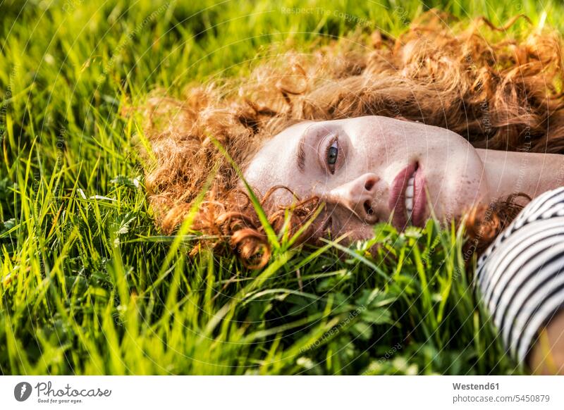 Portrait of redheaded young woman lying on meadow females women portrait portraits meadows laying down lie lying down Adults grown-ups grownups adult people