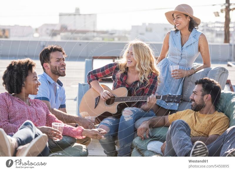 Friends having a rooftop party and playing guitar roof terrace deck laughing Laughter Party Parties friends guitars celebrating celebrate partying positive