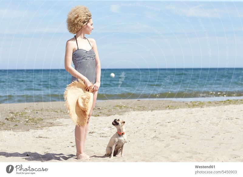 Young woman in swimsuit with straw hat and dog on the beach dogs Canine females women beaches pets animal creatures animals Adults grown-ups grownups adult
