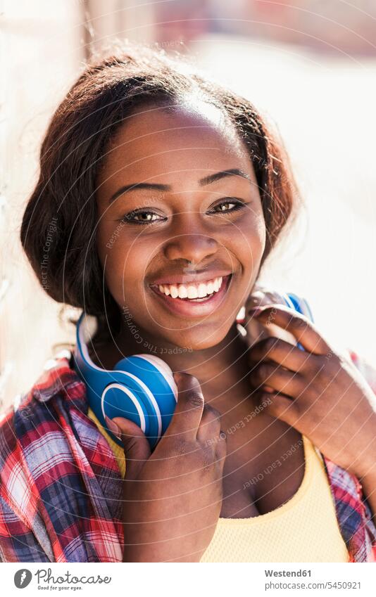 Portrait of a happy young woman with headphones around her neck cheerful gaiety Joyous glad Cheerfulness exhilaration merry gay happiness portrait portraits
