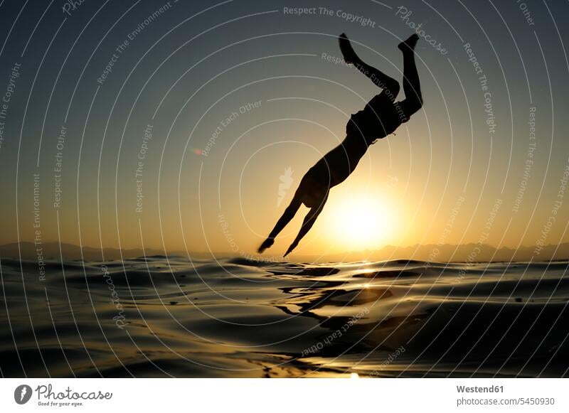 Man jumping into the sea at sunset Leaping man men males ocean vacation Holidays jumps Adults grown-ups grownups adult people persons human being humans