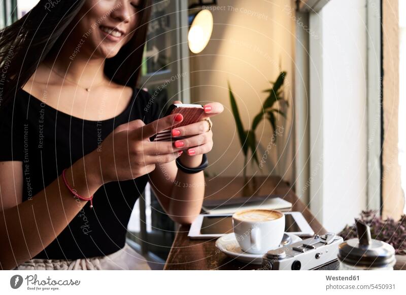Smiling asian woman chatting with her phone in a coffee shop next to the window Smartphone iPhone Smartphones female Asian female Asians smiling smile Coffee