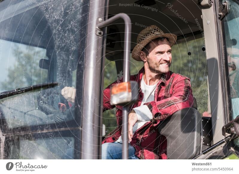 Smiling farmer on tractor man men males smiling smile agriculturists farmers Adults grown-ups grownups adult people persons human being humans human beings