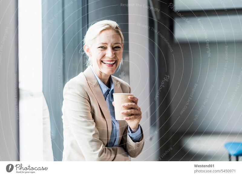 Portrait of happy businesswoman with coffee at the window Coffee portrait portraits laughing Laughter businesswomen business woman business women Drink