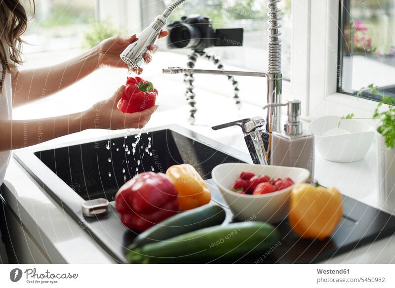 Woman washing vegetables at kitchen sink cameras cook domestic kitchen kitchens Alimentation food Food and Drinks Nutrition foods Vegetables bell peppers