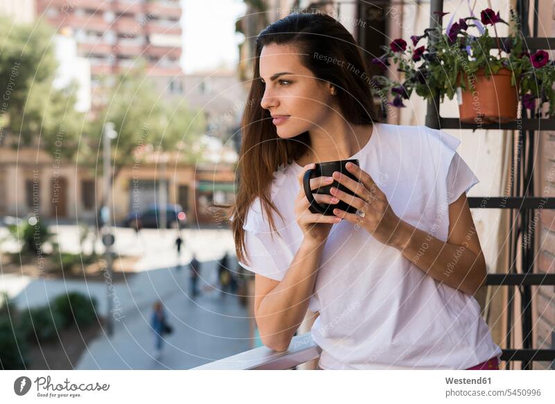 Woman with coffee mug standing on balcony looking at distance woman females women balconies Adults grown-ups grownups adult people persons human being humans