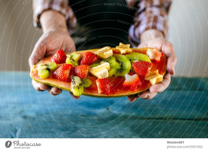Close-up of man's hands with half papaya with pieces of banana, kiwi and strawberries men males preparation prepare preparing Papaya Pawpaw Papayas Pawpaws
