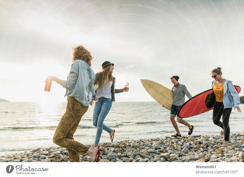 Happy friends with surfboards walking on stony beach happiness happy surfer surfers beaches friendship surfing surf ride surf riding Surfboarding water sports