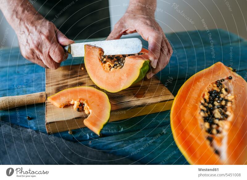 Hands of senior man cutting papaya healthy eating nutrition men males half halves halved Papaya Pawpaw Papayas Pawpaws Freshness fresh knife knives preparation