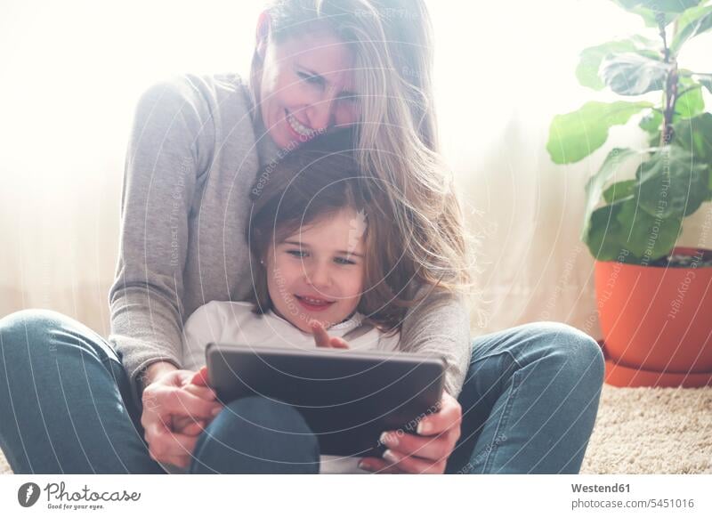 Mother and little daughter using tablet at home daughters mother mommy mothers ma mummy mama child children family families people persons human being humans