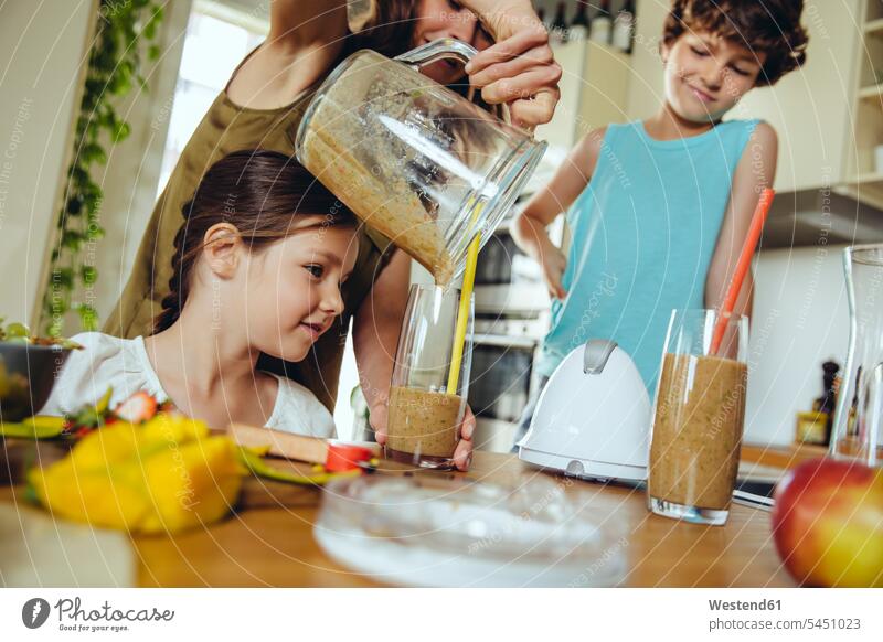 Mother with two children pouring a smoothie into glasses mother mommy mothers ma mummy mama Smoothies kitchen parents family families people persons human being