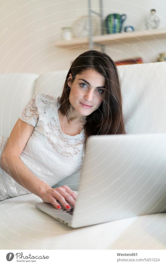 Portrait of woman on couch with laptop Laptop Computers laptops notebook settee sofa sofas couches settees females women computer computers Adults grown-ups