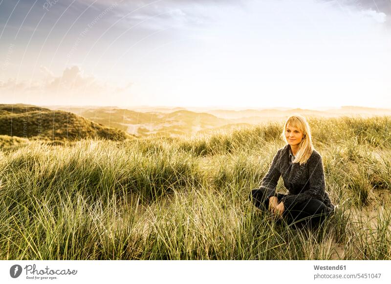 Smiling woman sitting in dunes beach beaches sand dune sand dunes smiling smile females women Seated Adults grown-ups grownups adult people persons human being
