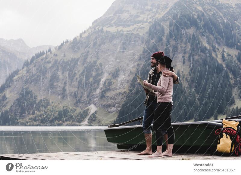 Austria, Tyrol, Alps, couple with map standing on jetty at mountain lake twosomes partnership couples smiling smile lakes people persons human being humans