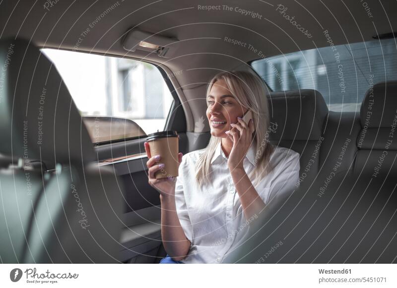 Smiling businesswoman with takeaway coffee on cell phone in car on the phone call telephoning On The Telephone calling automobile Auto cars motorcars