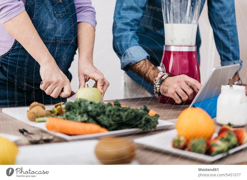 Hands of couple preparing fruits and using tablet for preparing smoothies twosomes partnership couples people persons human being humans human beings