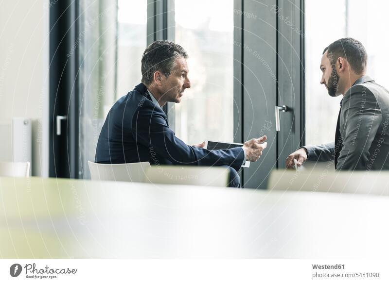 Two businessmen talking in office at the window speaking windows offices office room office rooms Businessman Business man Businessmen Business men workplace