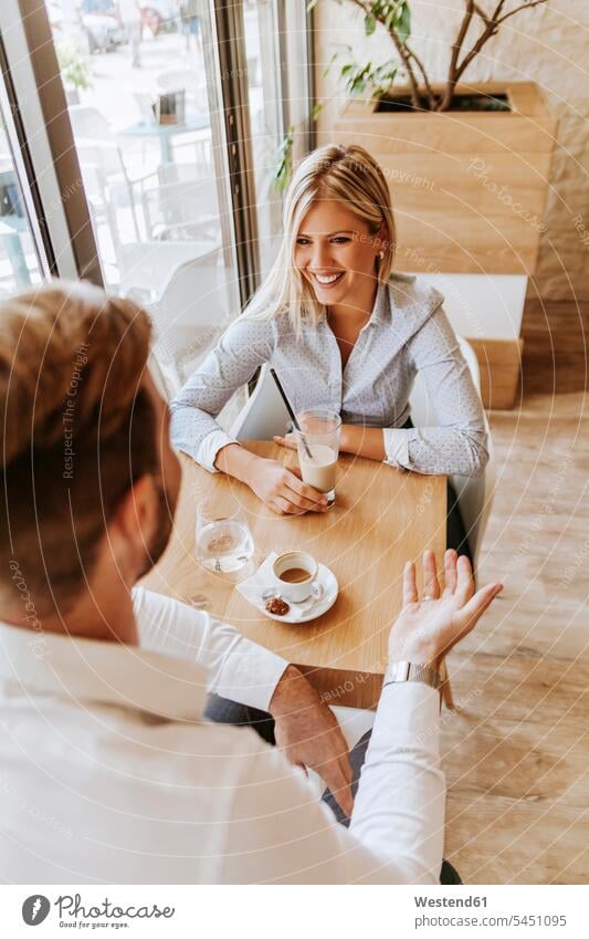 Happy young woman looking at man in a cafe couple twosomes partnership couples talking speaking laughing Laughter people persons human being humans human beings