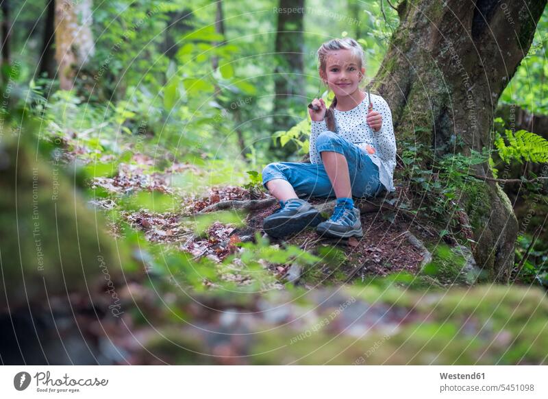 Portrait of smiling little girl in the woods forest forests females girls child children kid kids people persons human being humans human beings sitting Seated