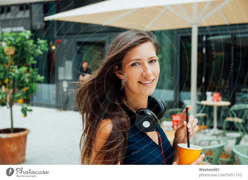 Portrait of smiling young woman with headphones and takeaway drink in the city headset smile females women portrait portraits Adults grown-ups grownups adult
