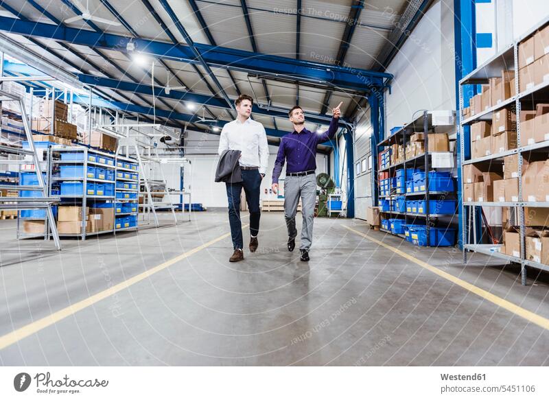 Two businessmen walking through shop floor, talking discussing discussion Meeting Meetings Business Meeting production hall business people businesspeople