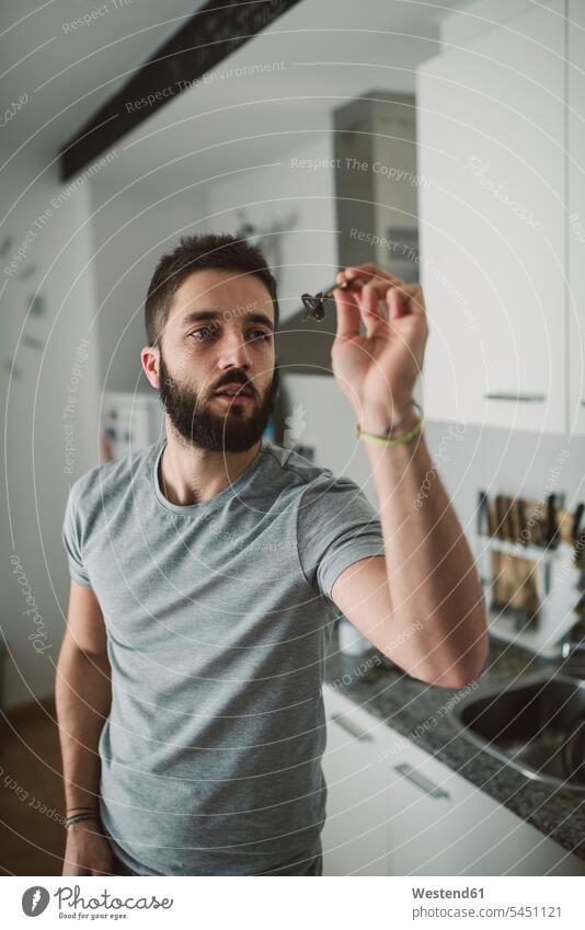 Young man playing darts in his kitchen young aiming standing throwing home at home men males dexterity game game of skill dexterity games games of skill Adults