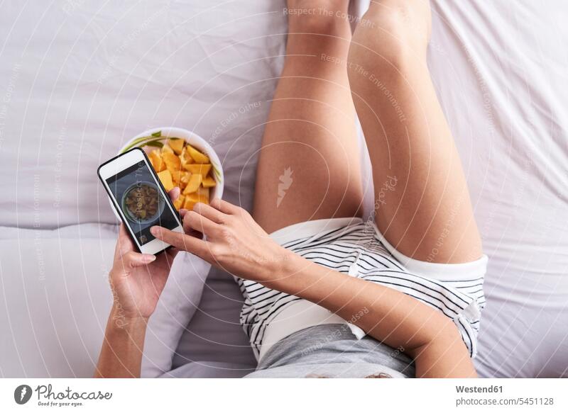 Close-up of woman taking a photo of a fruit bowl in bed Bowl Bowls beds Fruit Fruits mobile phone mobiles mobile phones Cellphone cell phone cell phones