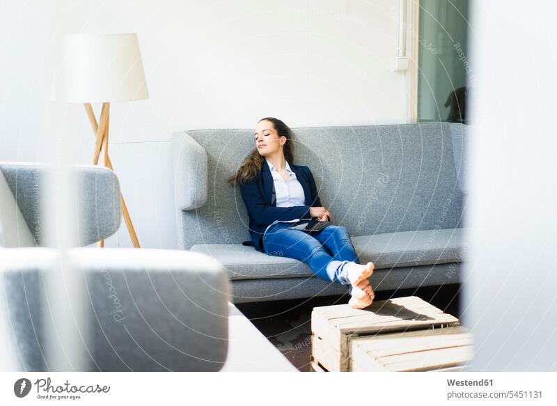 Businesswoman sitting on couch relaxing females women relaxed relaxation businesswoman businesswomen business woman business women Adults grown-ups grownups