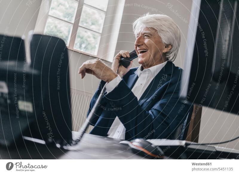 Laughing senior businessman on the phone in his office Businessman Business man Businessmen Business men offices office room office rooms call telephoning