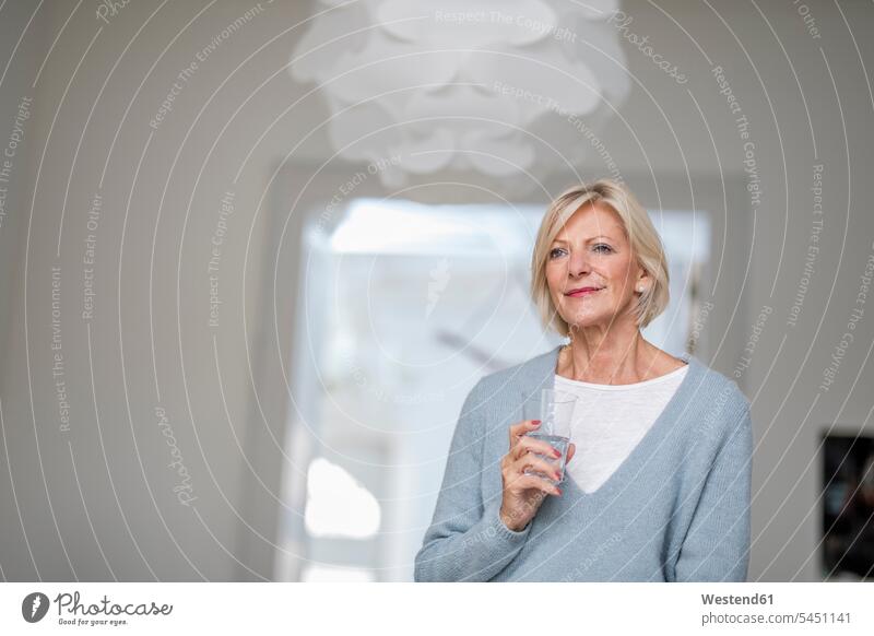 Portrait of relaxed senior woman with glass of water at home senior women elder women elder woman old females portrait portraits senior adults Adults grown-ups