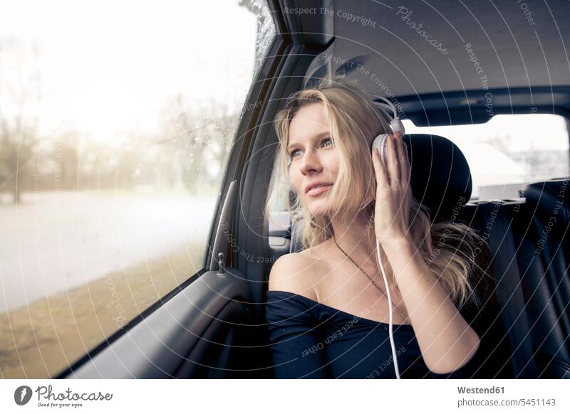 Portrait of young woman sitting in car listening music with headphones automobile Auto cars motorcars Automobiles headset females women motor vehicle