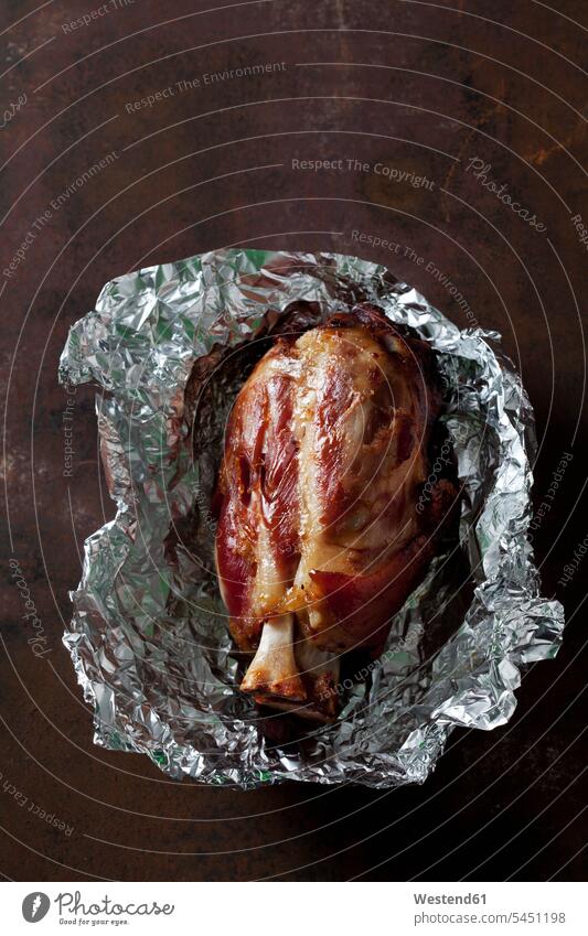 Roasted knuckle of pork in aluminium foil on a baking tray overhead view from above top view Overhead Overhead Shot View From Above cooking hearty savoury food