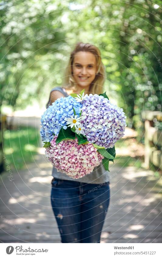 Smiling young woman showing a bouquet of hydrangeas and daisies Showing smiling smile Flower Flowers Bunch of Flowers Bouquet Flower Bouquet Bouquet of Flowers