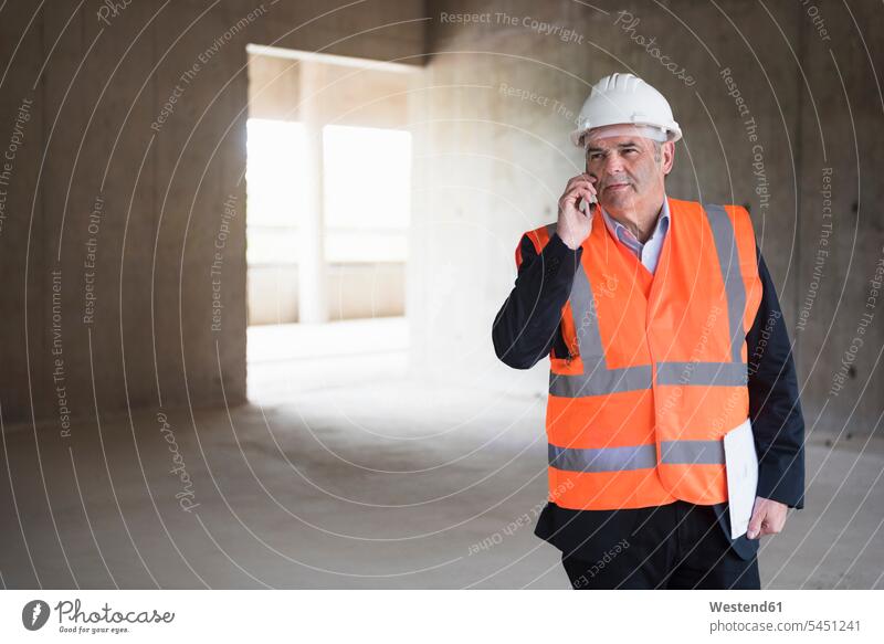 Man on the phone wearing safety vest in building under construction mobile phone mobiles mobile phones Cellphone cell phone cell phones architect architects man
