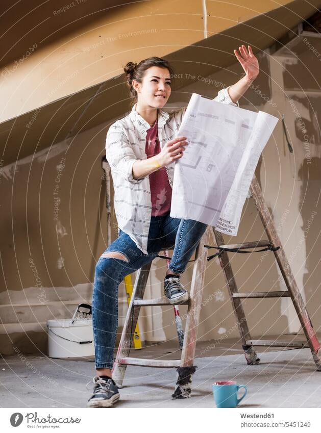 Young woman renovating her new home, holding construction plan home ownership private owned home renovation renovate refurbish refurbishing Renovations