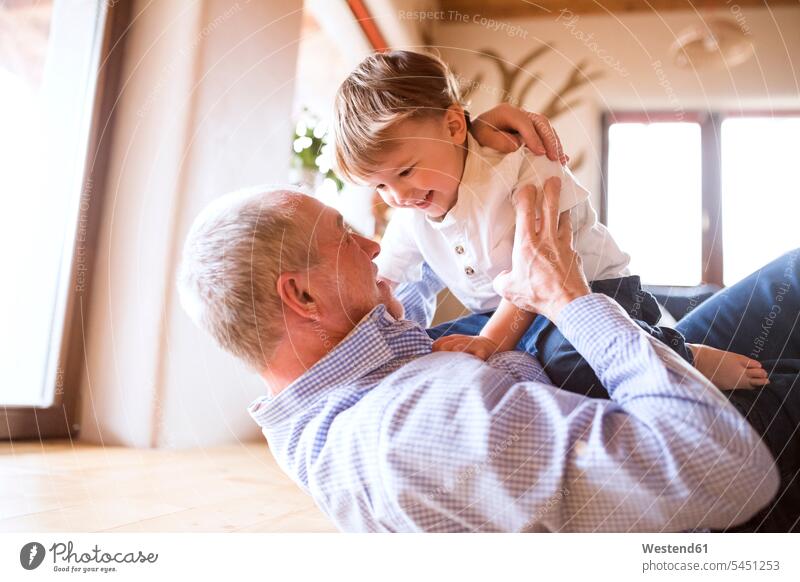 Grandfather and grandson having fun at home together playing playfighting play fighting Romping grandsons grandfather grandpas granddads grandfathers grandchild