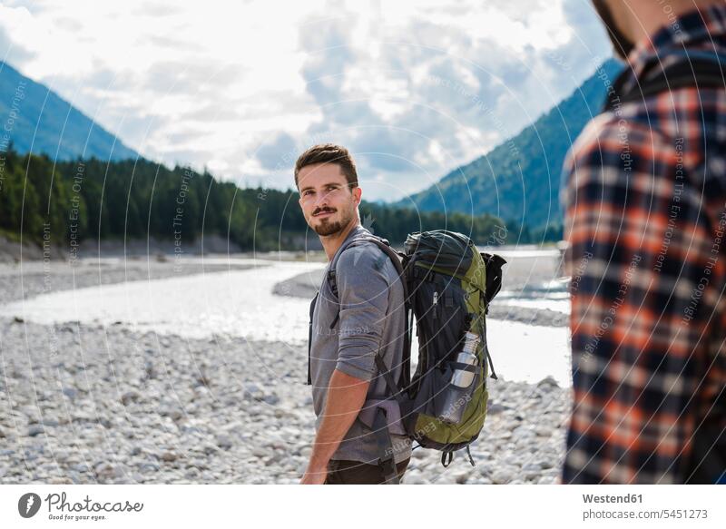 Germany, Bavaria, portrait of young hiker with backpack looking at his friend portraits friends friendship standing eyeing rucksacks backpacks back-packs