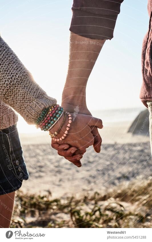 Portugal, Algarve, close-up of couple holding hands at sunset on the beach human hand human hands twosomes partnership couples beaches people persons